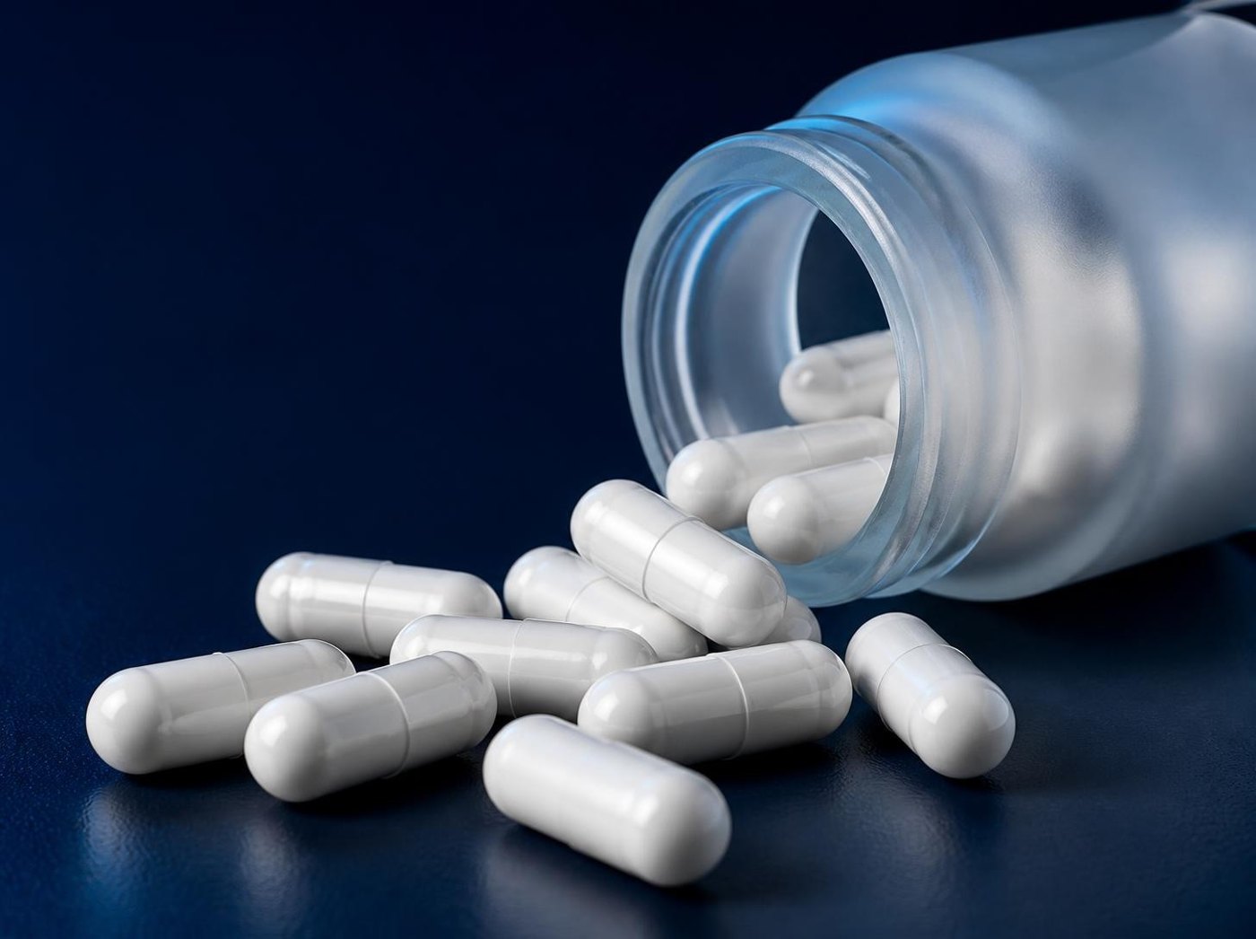 White capsules spilling from a frosted jar